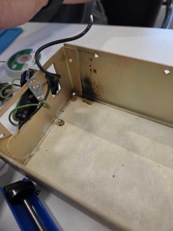 Inside of the metal power supply, a dark black smudge is present near the back corner where the capacitor blew.