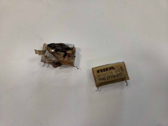 Two yellow RIFA capacitors, one exploded and leaking dark goop.