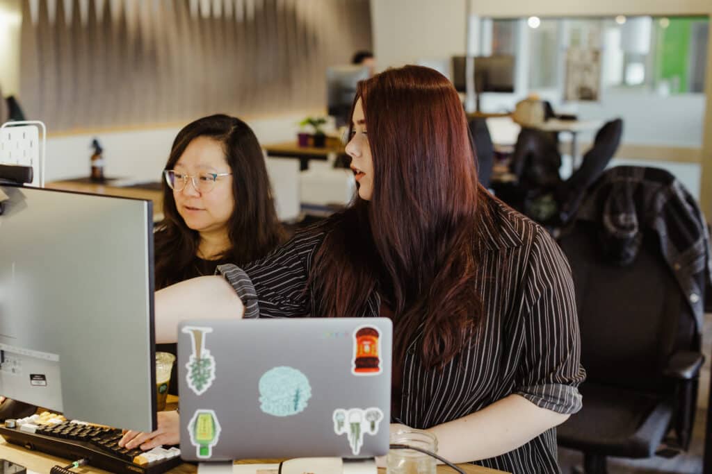 Author Maria Irimie and a co-worker look at a monitor together. Post title: My Encyclopedia is Human