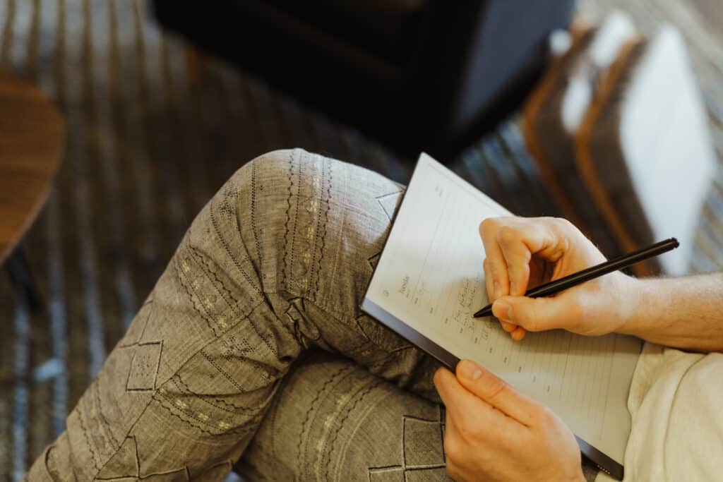 Pictured is a hand with a pen writing in a notebook, illustrating a point "Retake Your Pen" from the article Crucial Conversations: In the Heat of It