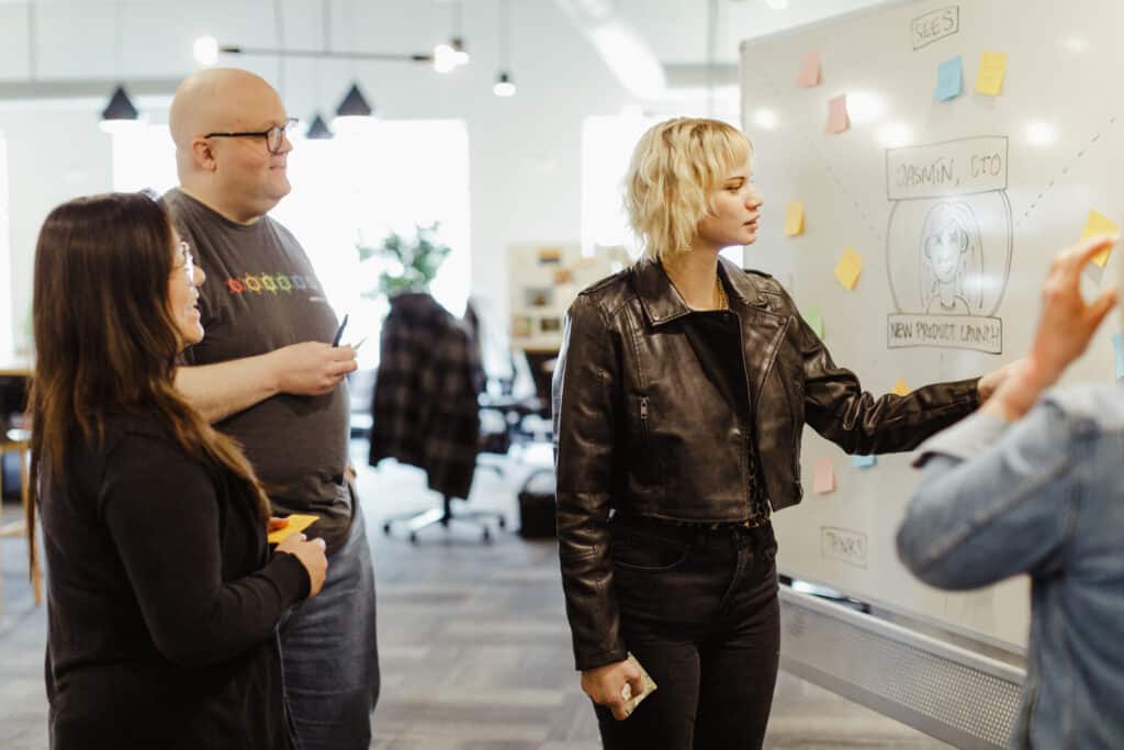 Author Mattie Behrens with Atomic Object Teammates discussing a problem. Post title: Don't Hide Useful Conversations in Private Messages