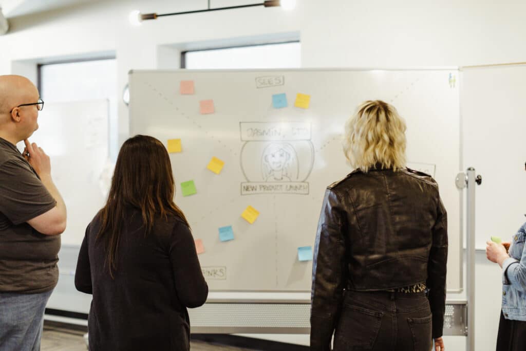 Three developers at a whiteboard. Post title: What Constitutes a Meal? What Constitutes an Active User?
