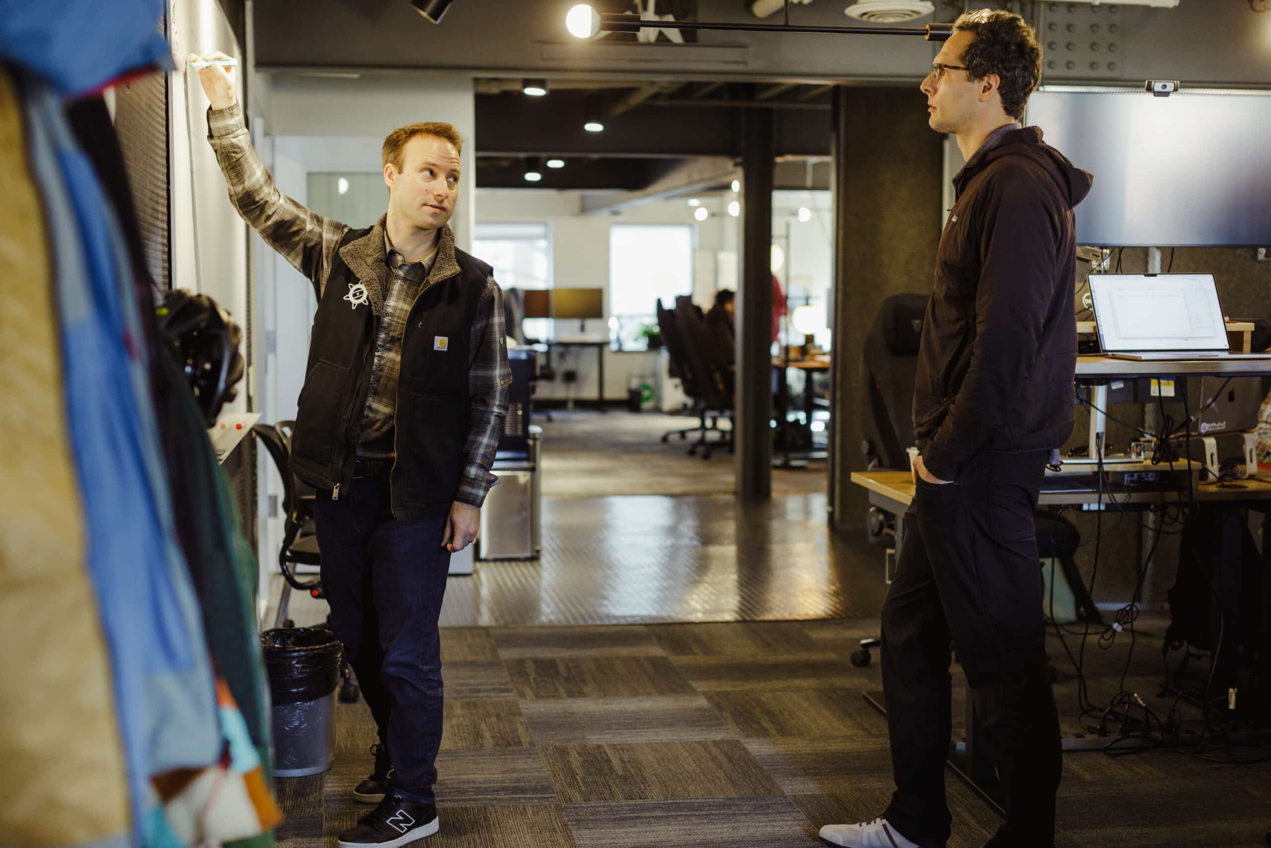 Pictured is author John Fisher talking to a co-worker. Post title: Beyond Code: Using Cursor IDE for Knowledge Management