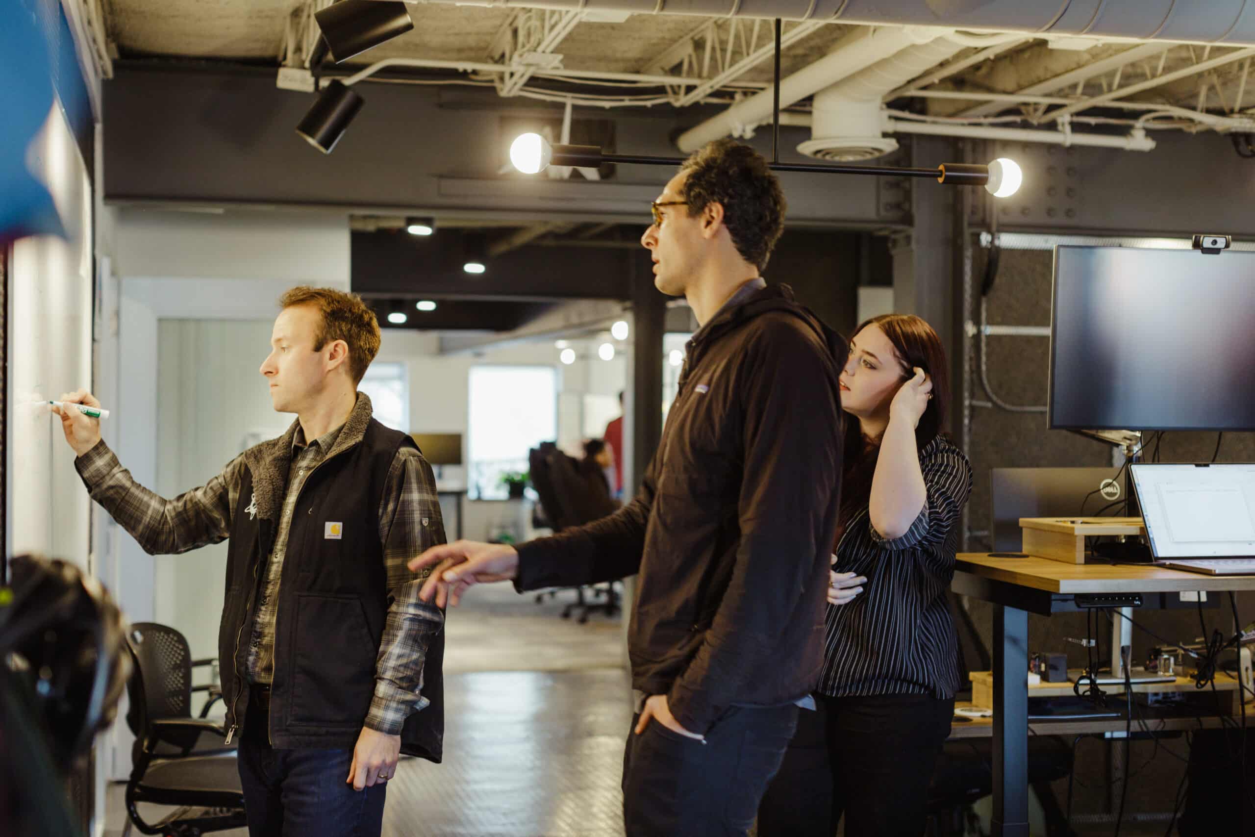 Shown are Atomic object employees talking at a whiteboard. Post title: Why Your Team Retro Needs a Clear Intention