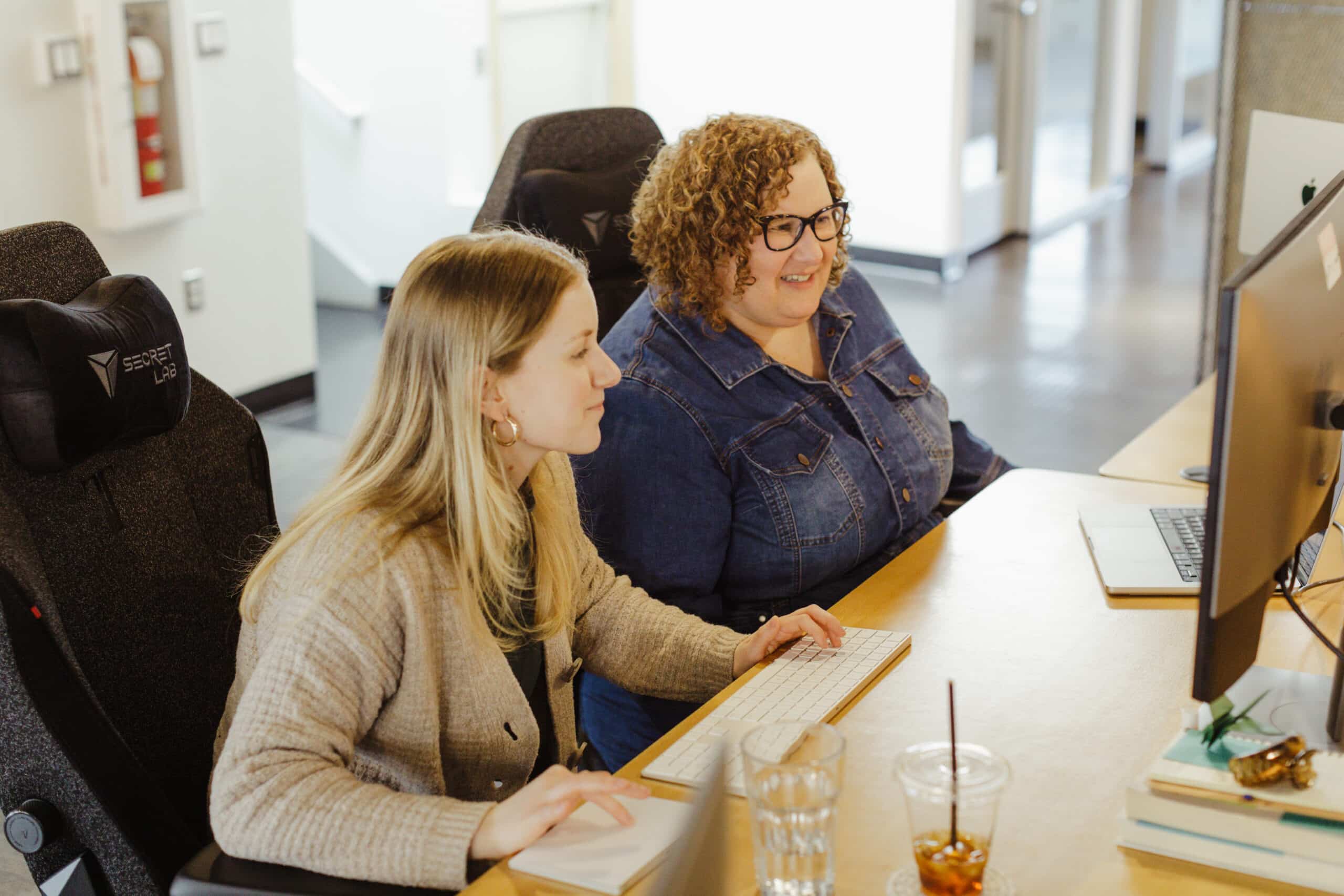 Two women pairing in front of a single computer.