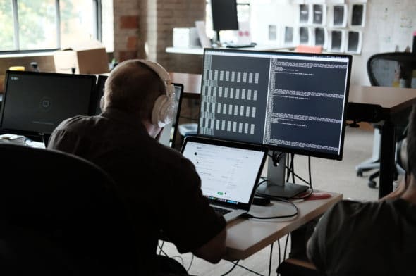 Person coding in front of multiple screens.