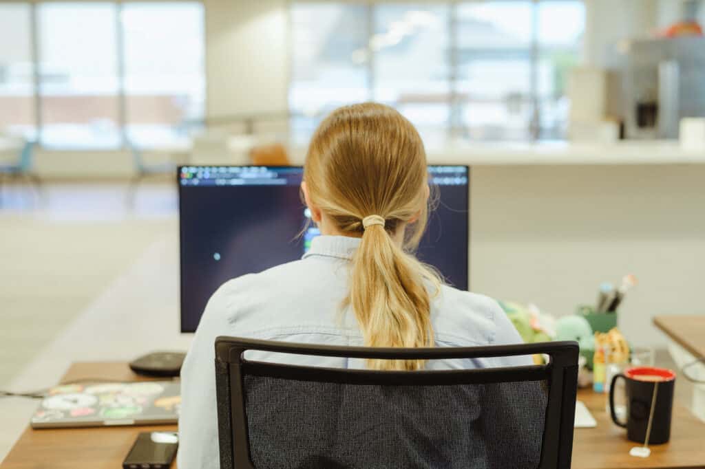 Pictured is author Danielle Wisen at her computer. Post title: Add Custom Claims Using Auth0 Actions