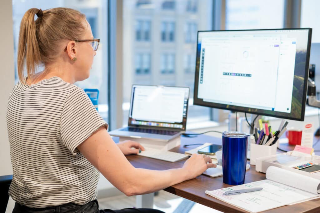 Pictured is a designer at her desk. Post title: Designers Aren't Going Anywhere. Here's Why.