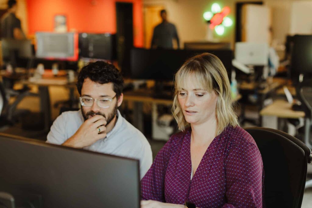 Author Meg Kretz looks at a monitor with a co-worker. Post title: Spec-Driven Development Is Not Waterfall