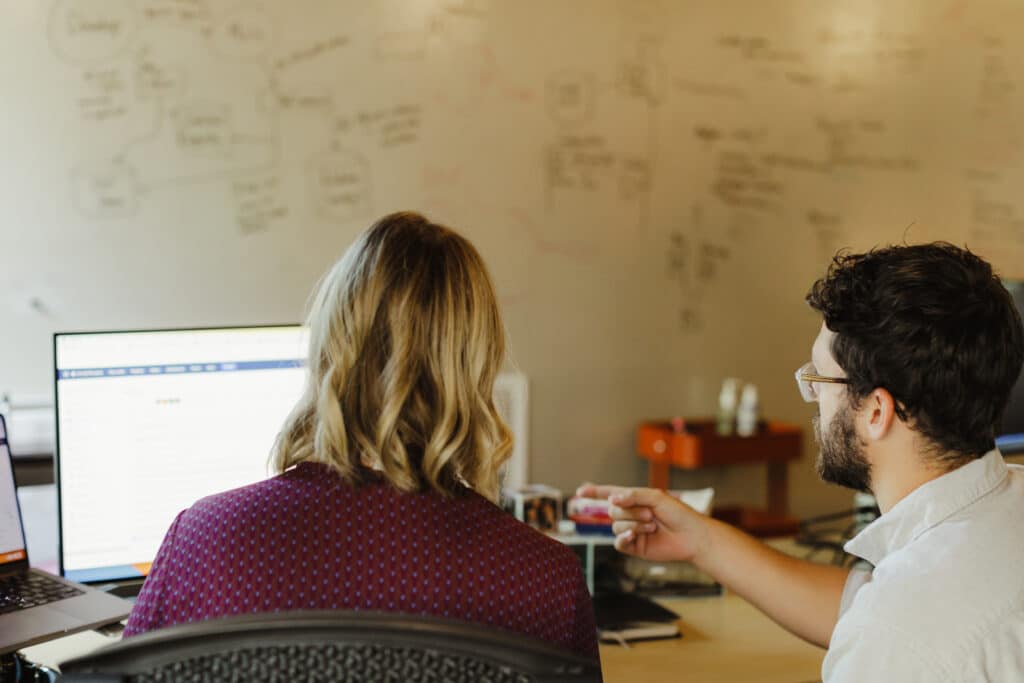 Two developers looking at a monitor together. Post title: CancellationToken in C# - Pitfalls and Winning Patterns