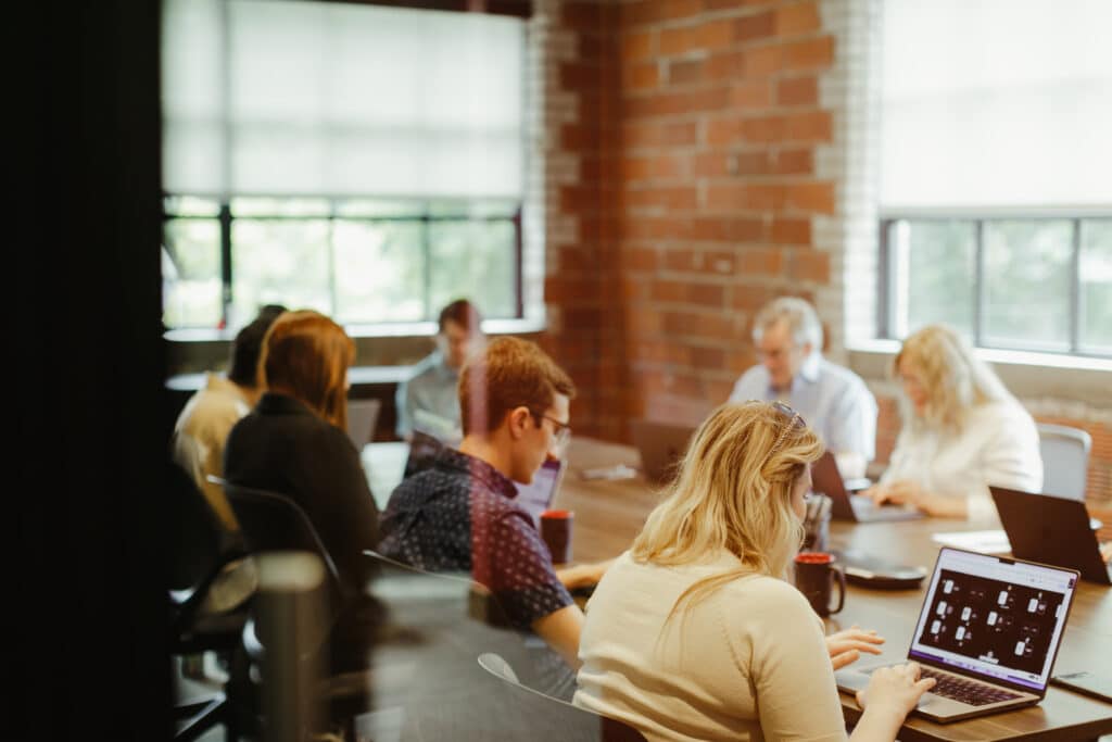 A team of Atomic Object developers sit around a table. Post title: Shipping Faster Doesn’t Necessarily Mean Learning Faster