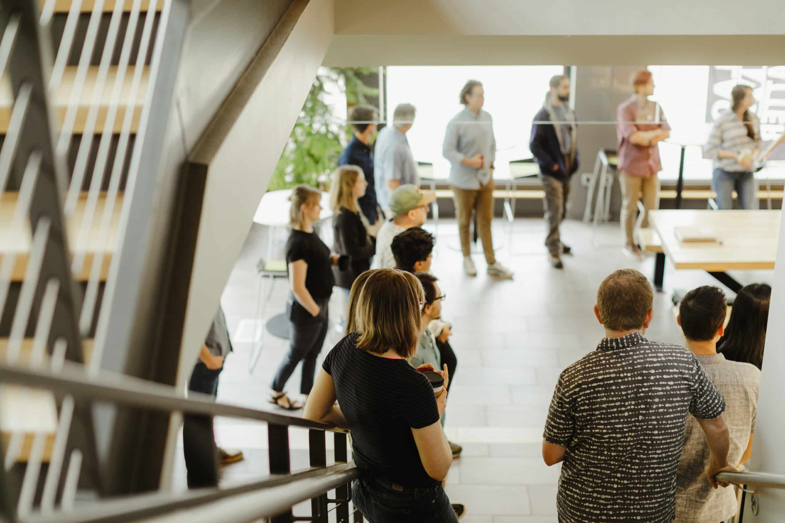 Pictured is the Atomic Object team at a standup meeting. Post title: In the World of Artificial Intelligence, Practice Human Intelligence