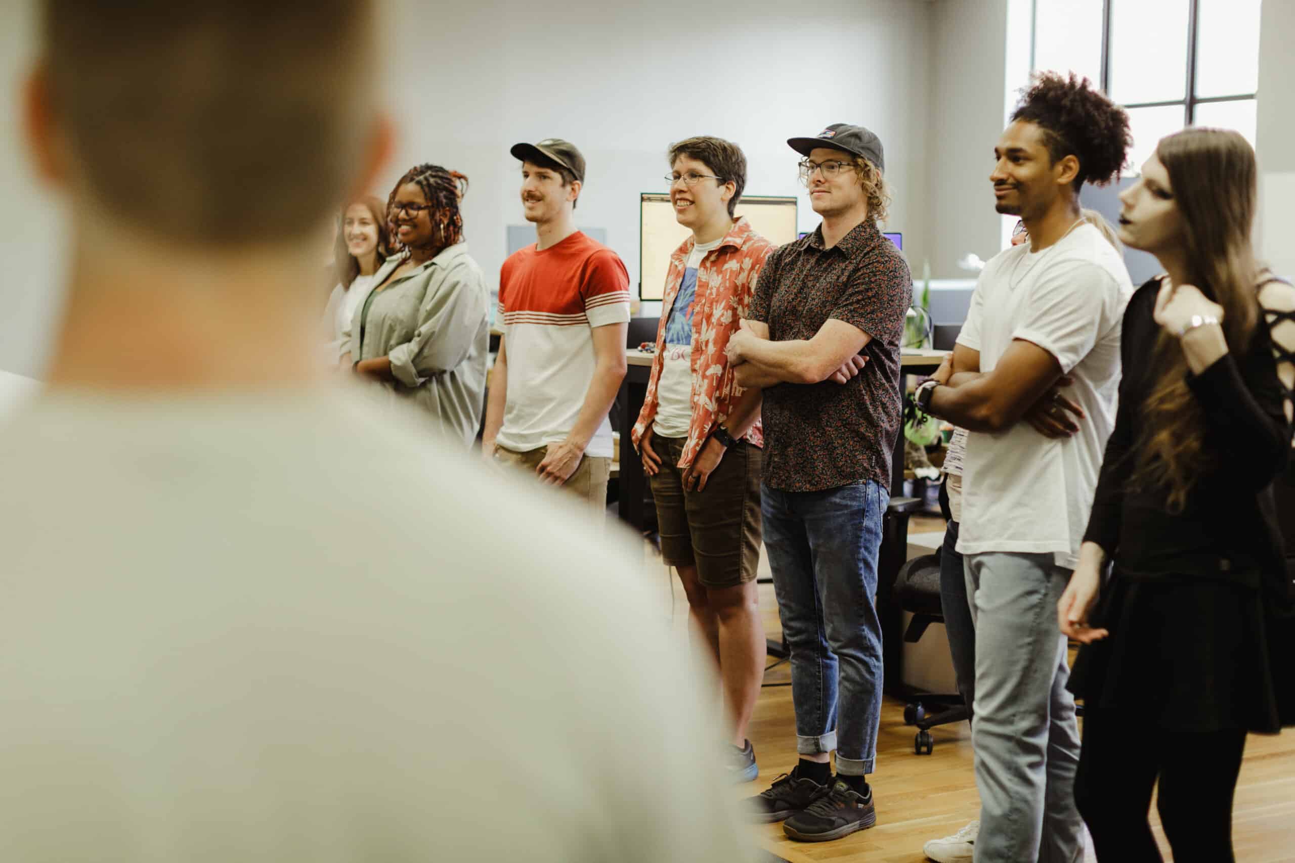 Author Jacob Williams is shown in a standup meeting with colleagues from Atomic Object. Post title: Accelerator Program FAQ, Answered by an Alum