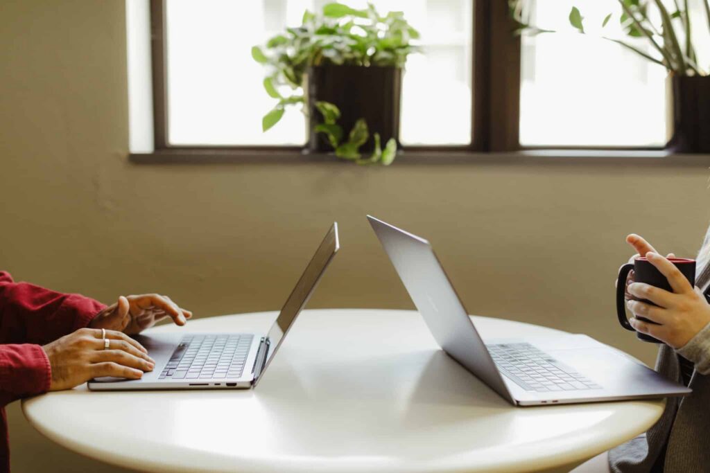 Two developers sit at a table with laptops, one holding a mug. Post title: Human Maintainable Code in the Age of AI Agents