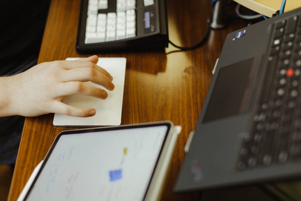 A developer's hand on a trackpad for a computer. Post title: How I Created a Security Advisory with GitHub