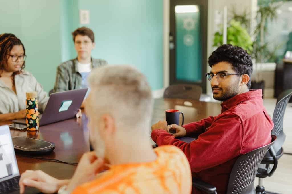 Four people sit at a meeting table