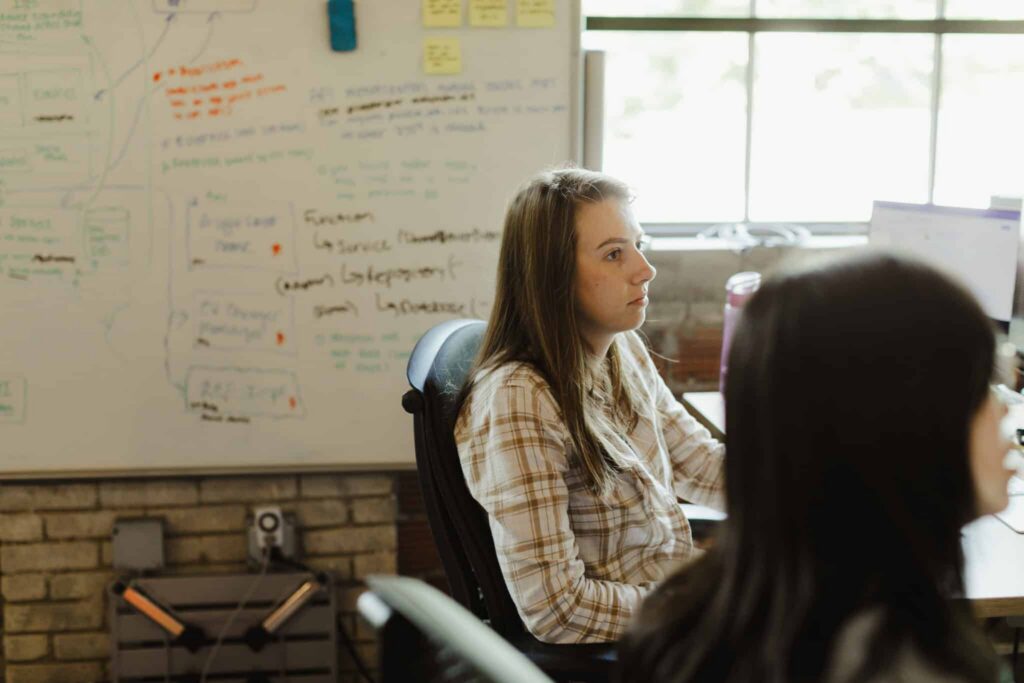 Pictured is post author Kelsey Brennan with a colleague. Post title: Our AI Code Review Workflow, 7 Months Later