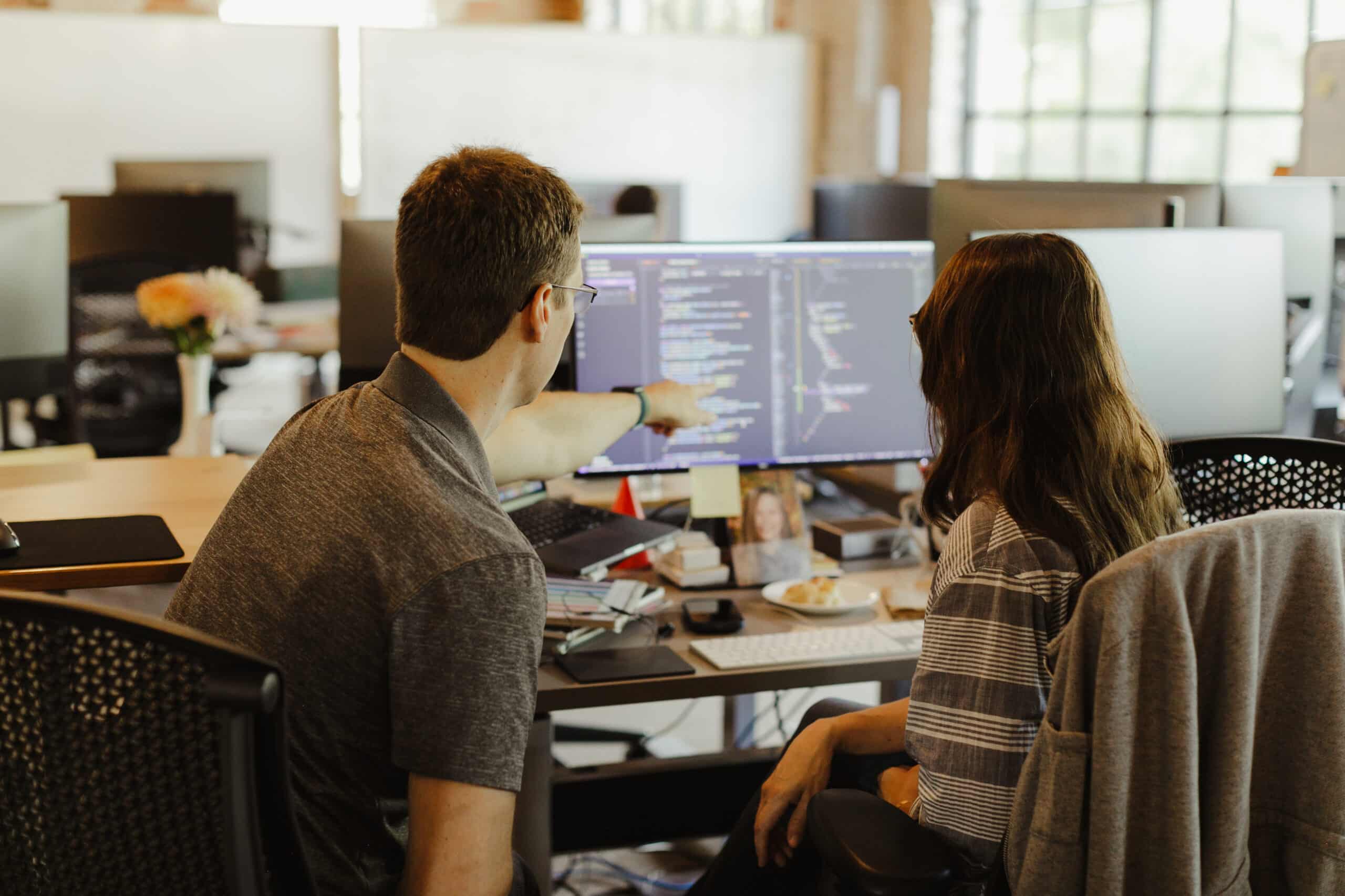Two developers look at a monitor together. Post title: The Perfectly Implemented Misunderstanding