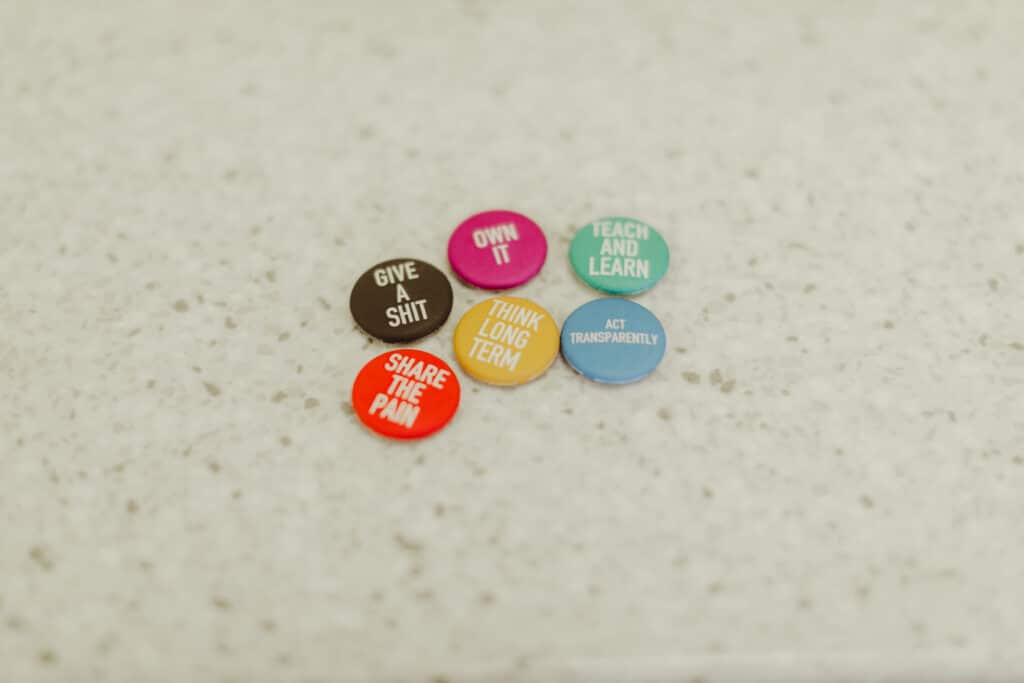 Pictured are buttons with Atomic Object's values written on them, including "Share the Pain."