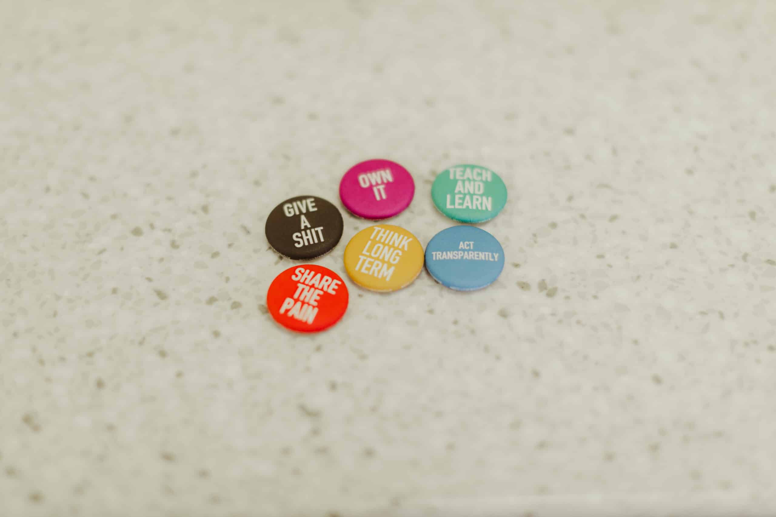 Pictured are buttons with Atomic Object's values written on them, including "Share the Pain."
