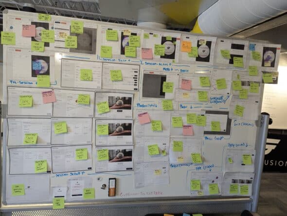 The same whiteboard as before with multiple yellow, orange, blue and pink sticky notes however every design photo has a green sticky note on it