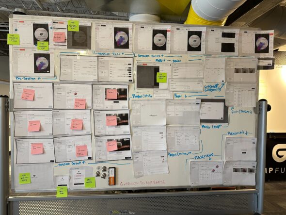 The same whiteboard as before with the designs but now with 7 green sticky notes and 9 pink sticky notes