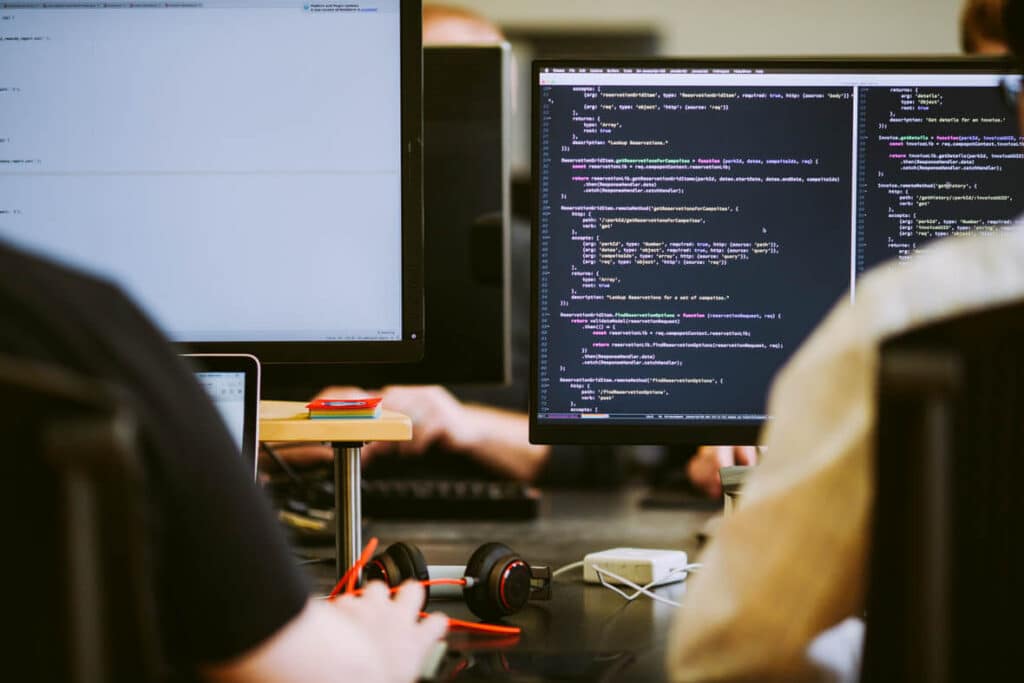 Two developers look at a monitor of code. Post title: Make HIPAA Compliance More Accurate and Easier with Automation