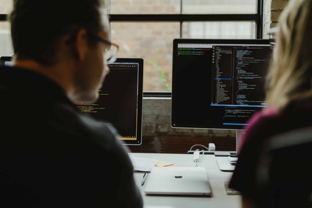 Two developers look at a monitor together. Post title: 4 Terminal Tools I Recommend to New Developers