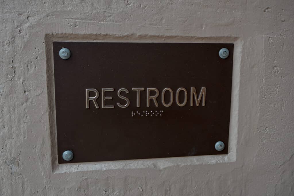 Pictured is a sign saying "Restroom" with Braille under the words. Post title: PottyMon: Keeping the Tradition Alive